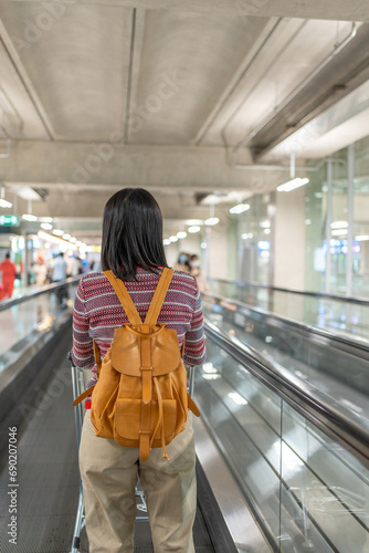 Asian woman standing on electric walkway in airport going to airplane gateway