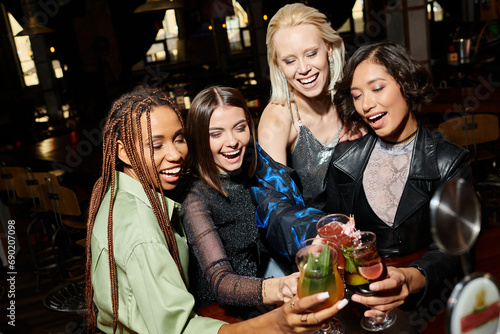 excited and young multicultural women clinking delicious cocktails in bar  happy party time