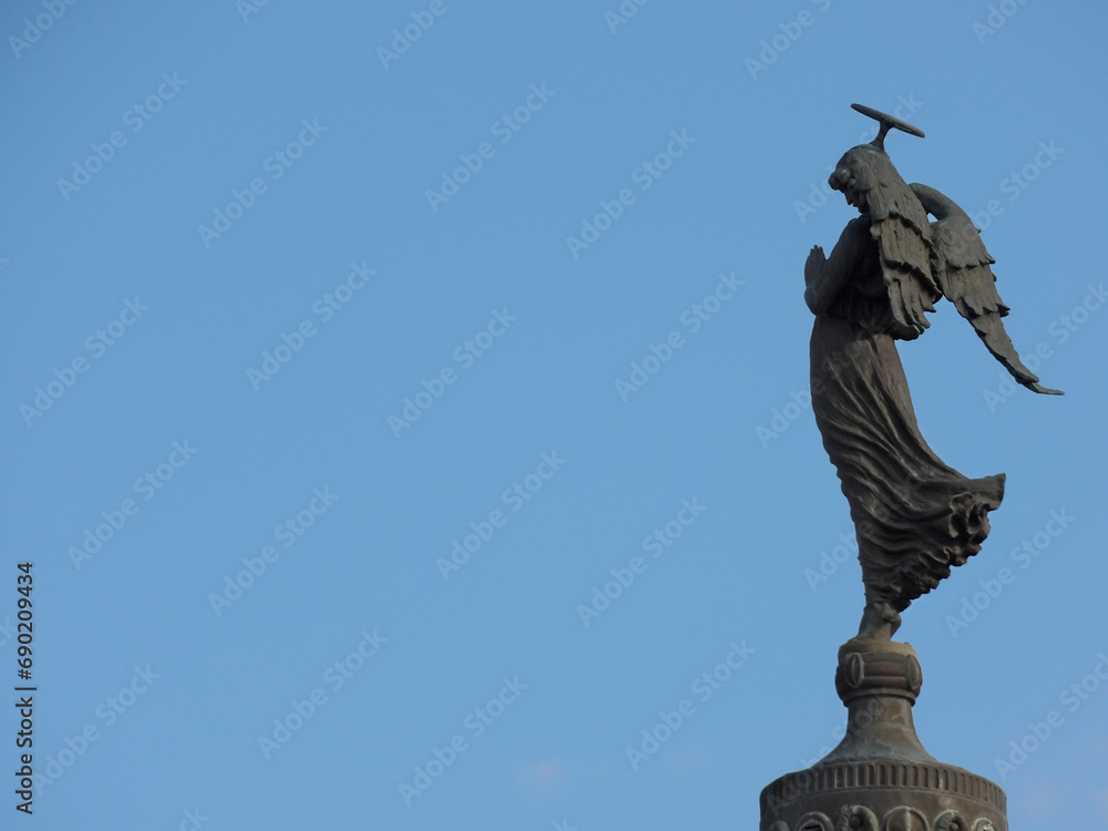 Bronze statue of a figure with a hammer in hand, standing atop a tall building