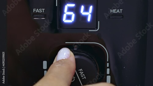 Female hand turning on the water heater temperature regulator in the bathroom. Water temperature display in the electric boiler close up photo