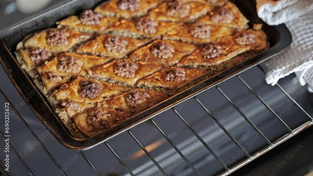 Baklava with honey sauce. The confectioner takes the freshly baked baklava out of the oven. Traditional Arabic dessert Baklava with honey sauce. The confectioner takes the freshly baked baklava out of the oven. Traditional Arabic dessert