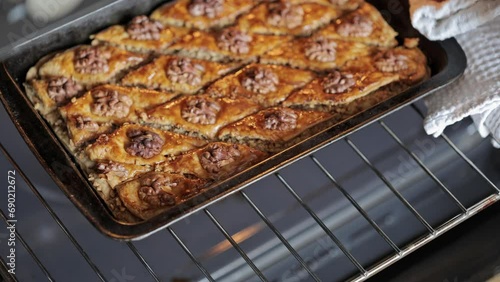 Baklava with honey sauce. The confectioner takes the freshly baked baklava out of the oven. Traditional Arabic dessert