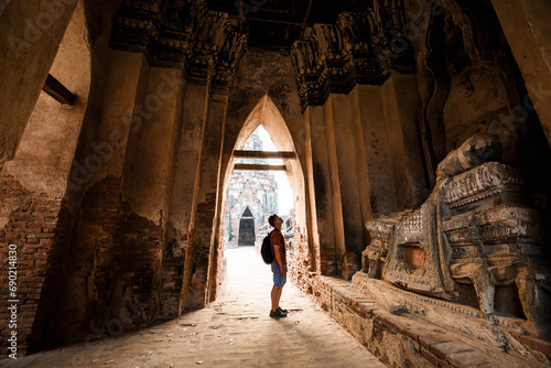 Tourist male shoulder bag walking near ancient ruined stupa with photo camera in Ayutthaya © chitsanupong