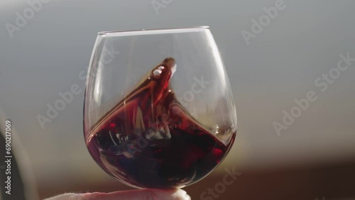 Tasting a wine in cellar. Close up of female hand sommeler swirling the glass to make the wine spinning, cinematic isolated slow motion shot