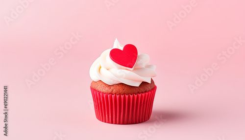 Muffin (cake) decorated with cream and a  red  heart for Valentine's Day on a pink background
