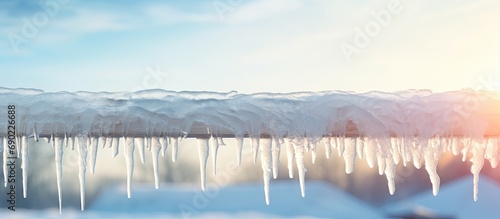 Ice dam in gutter and ice frozen on roof in winter focus on icicles in foreground. Website header. Creative Banner. Copyspace image photo