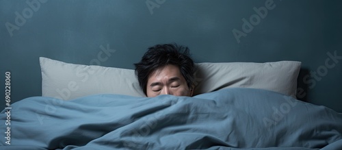 Frustrated unhappy depressed middle aged asian man wearing pajamas sitting alone on bed at home covering his face experiencing midlife crisis going through divorce copy space. Website header