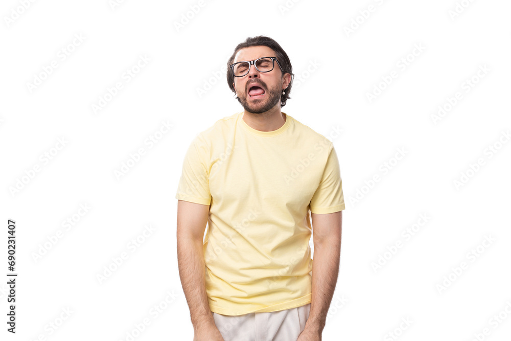 a young brutal European brunette guy with a beard and mustache dressed in a light yellow T-shirt stands on a white background with copy space a young brutal European brunette guy with a beard and mustache dressed in a light yellow T-shirt stands on a white background with copy space
