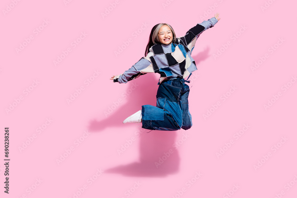 Full length photo of overjoyed cute youngster wear oversize sweatshirt jeans flying hold arms like wings isolated on pink color background