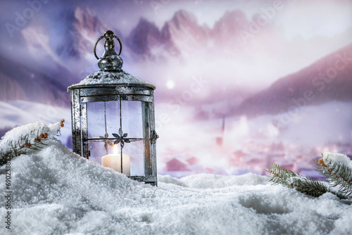 Winter snow background with lamp and candle. Empty space for your product. Warm light of fire. Chrismtas time and blurred landscape of mountains. Cold december time and mockup for your decoration.  © magdal3na