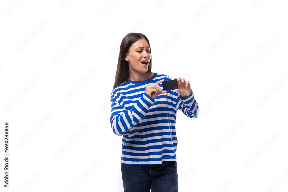 charming young brunette woman in a striped blue blouse holding a plastic credit card on a white background with copy space charming young brunette woman in a striped blue blouse holding a plastic credit card on a white background with copy space