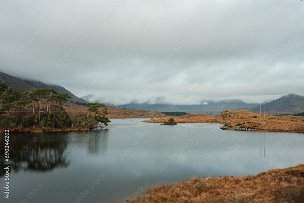 Connemara National Park in Ireland. Scenic drive on N59 route stretches beside the calm ocean water surrounded by mountains. Ireland