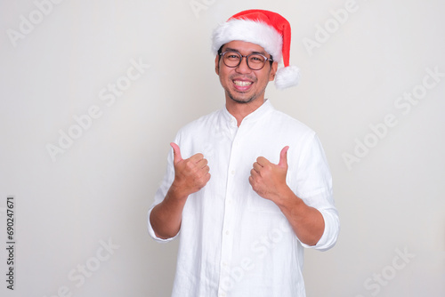 A man wearing christmas hat smiling happy and give two thumbs up photo