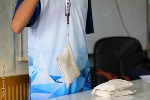 Asian students perform a physics experiment using a Spring Balance, a cylinder connected to a sandbag, and pulled up to measure the weight of the sandbag. Soft and selective focus.   photo