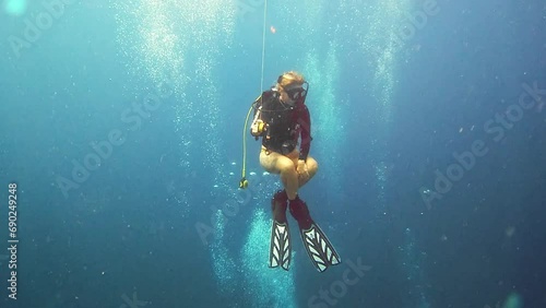 Woman, swimming and scuba diving in ocean to explore underwater and tropical holiday or eco vacation. Person or diver gas cylinder and bubbles to search deep blue water, sea life and nature adventure photo