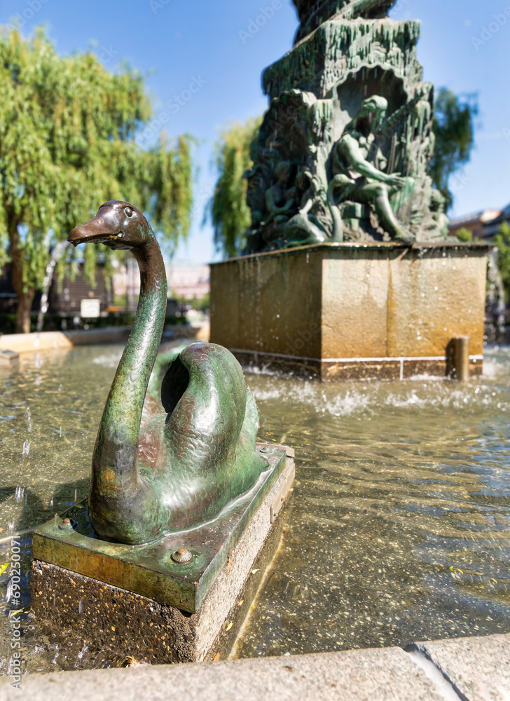 Close-up of the swan statue at the Molin's Fountain in Kungstradgarden, Stockholm, Sweden. The fountain is surrounded by lush green trees, creating a serene and peaceful scene Close-up of the swan statue at the Molin's Fountain in Kungstradgarden, Stockholm, Sweden. The fountain is surrounded by lush green trees, creating a serene and peaceful scene