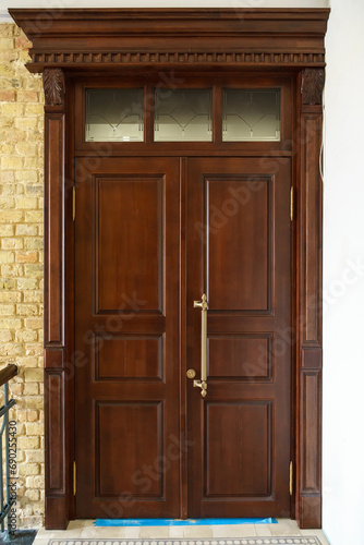 A closed wooden door inside. Interior design, dark red door with metal handle and lock. Evacuation exit © Pokoman