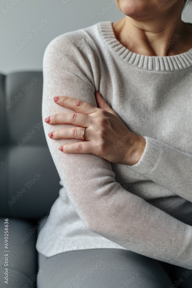 A woman sitting on a couch with her hands resting on her chest. This image can be used to depict relaxation, contemplation, or a moment of reflection A woman sitting on a couch with her hands resting on her chest. This image can be used to depict relaxation, contemplation, or a moment of reflection