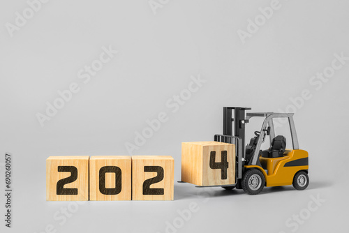 2024 happy new year background. new year industrial concept, forklift carrying box to complete 2024 text isolated on grey background.