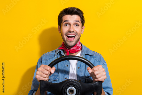 Photo portrait of nice young man hold steering wheel excited dressed stylish denim garment isolated on yellow color background