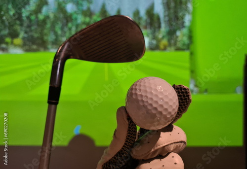 Golfer in glove holds golf ball and club indoors photo