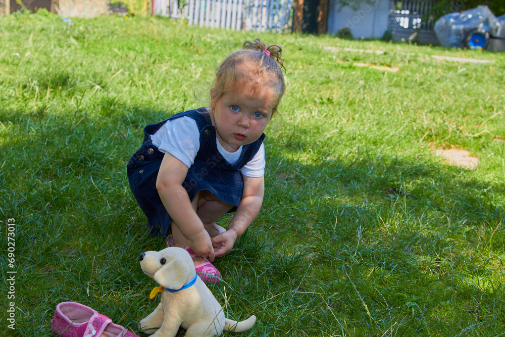 the child puts on shoes on the grass,a little girl puts on her sandals alone in the yard the child puts on shoes on the grass,a little girl puts on her sandals alone in the yard