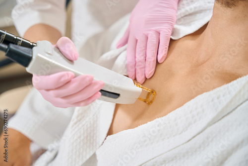 Male undergoing laser hair removal of chest in beauty salon