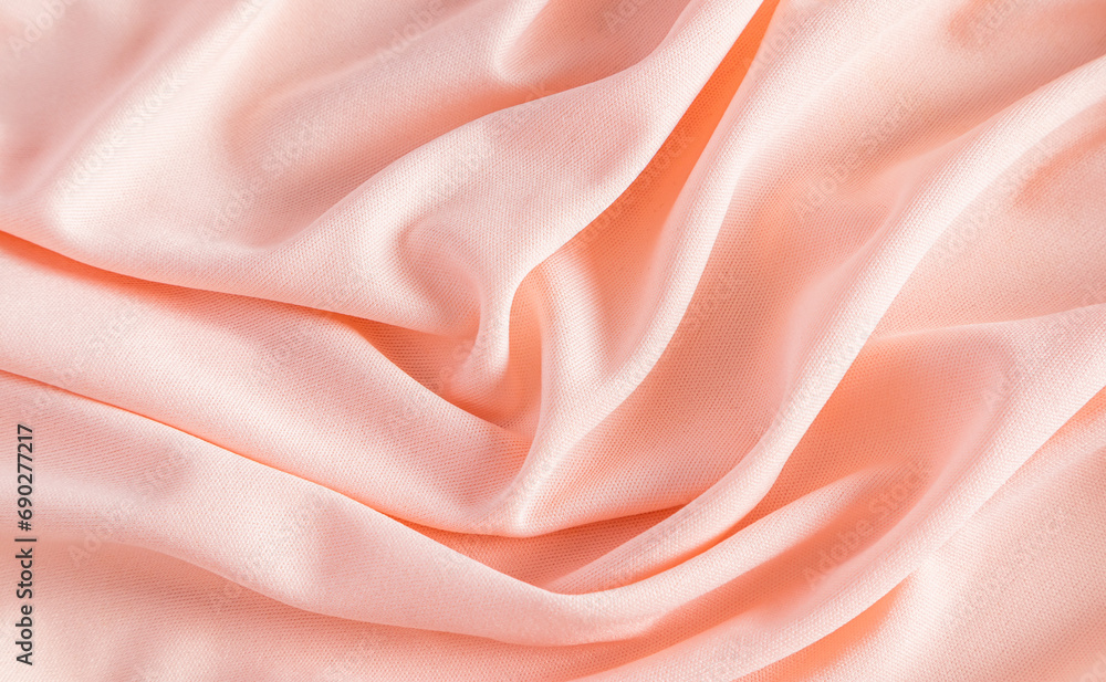 Fototapeta premium Elegant satin fabric with a peachy color. luxurious texture of the soft folds . festive background. design. color of the year peachy fuzz