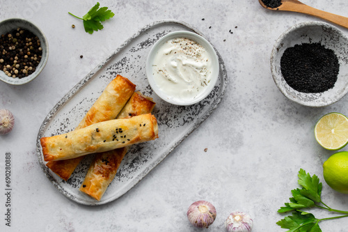 Turkish Cigara Börek (Sigara böreği) or Cigarette Pastry with Spinach and Feta Cheese with yogurt dip. Finger food. Spring rolls. Top view photo