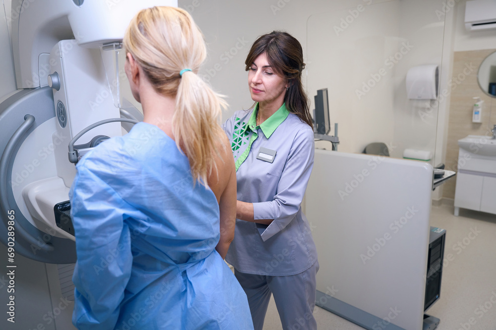 Fototapeta premium Experienced mammographer preparing woman for digital mammogram in clinic