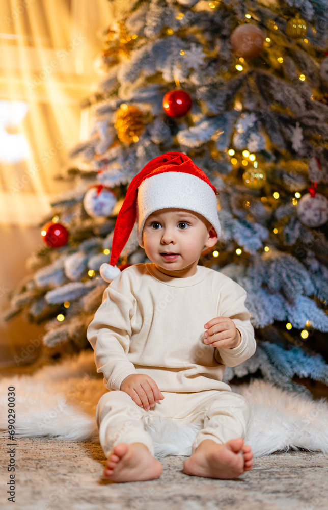 A baby sitting in front of a christmas tree. A Baby Sitting in Front of a Christmas Tree