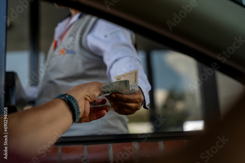 Male paying with cash at a toll booth in Colombia, South America. photo