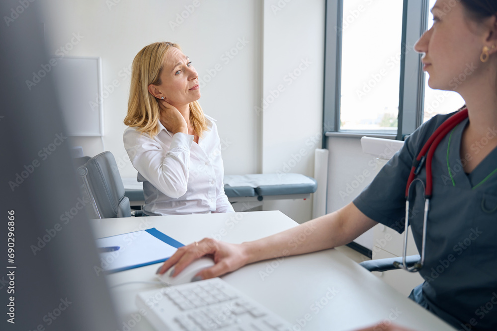 Low-spirited patient complaining of neck pain to doctor Low-spirited patient complaining of neck pain to doctor