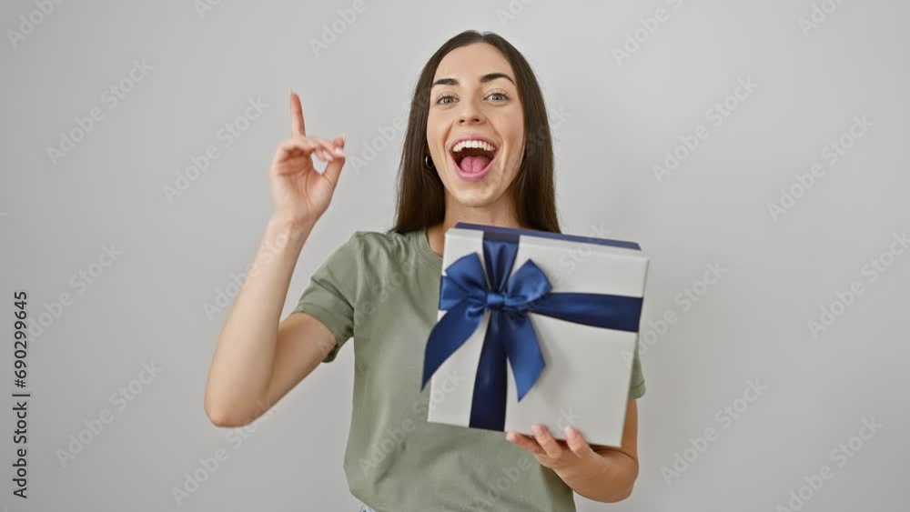 Excited young hispanic woman, flashing a brilliant smile, holds a birthday surprise gift. she points up, an idea sparking, surprised question on her beautiful face. isolated on white background. Excited young hispanic woman, flashing a brilliant smile, holds a birthday surprise gift. she points up, an idea sparking, surprised question on her beautiful face. isolated on white background.