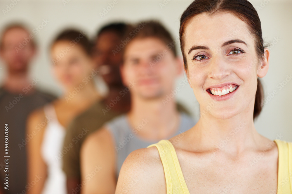 Portrait, smile or fitness and a woman with a group of people in a studio for health or wellness. Exercise, training and happy with a confident young person in gym class for the start of a workout