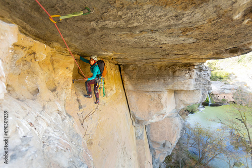 Person climbing in high mountains with yellow jacket rope and helmet in nature, confidence and risk, safety