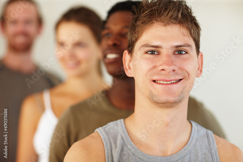 Portrait, smile or fitness and man with a group of people in a studio for health, wellness or mindfulness. Exercise, workout and pilates with a happy young person in gym class for holistic training © Daniel L/peopleimages.com