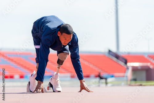 Front side view of sport man athlete with a prosthesis on his leg action of start to run on the track at the stadium. Sport concept.