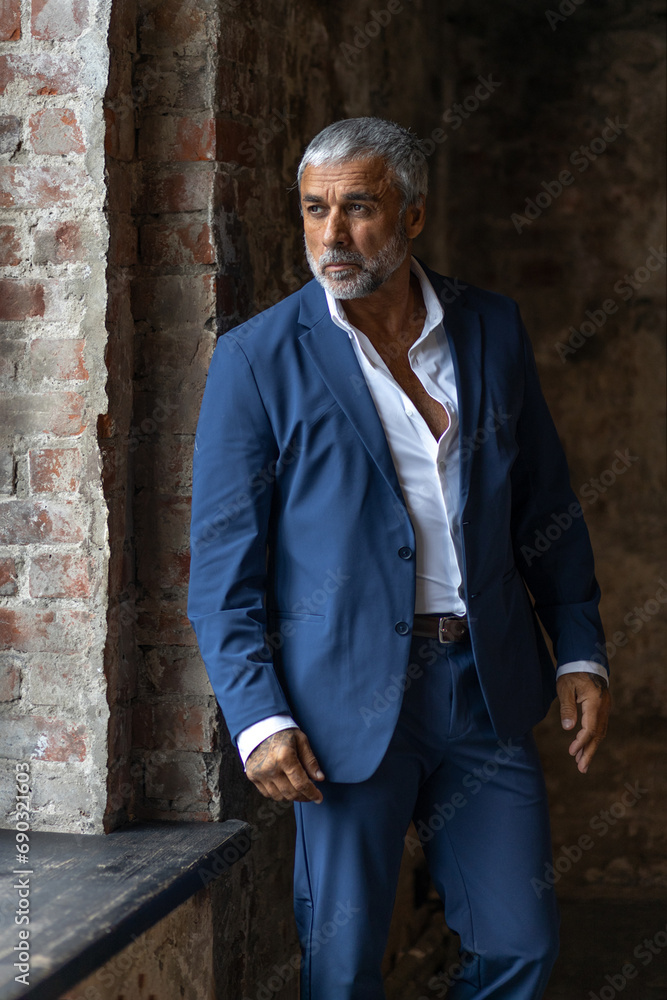 A handsome middle-aged man in a blue formal suit poses on a gray background. Portrait of a businessman. A handsome middle-aged man poses on a gray background with a place to copy A handsome middle-aged man in a blue formal suit poses on a gray background. Portrait of a businessman. A handsome middle-aged man poses on a gray background with a place to copy