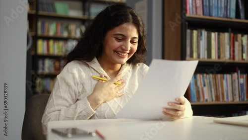 Portrait of happy student got an excellent grade mark for the test at university class Cute curly smiling girl looking at test in good mood indoors Exam passed Successful education concept photo