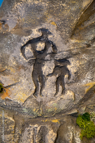 Black images of little men on the rocks on a clear sunny day. Paleontology of Early Cretaceous fossils.