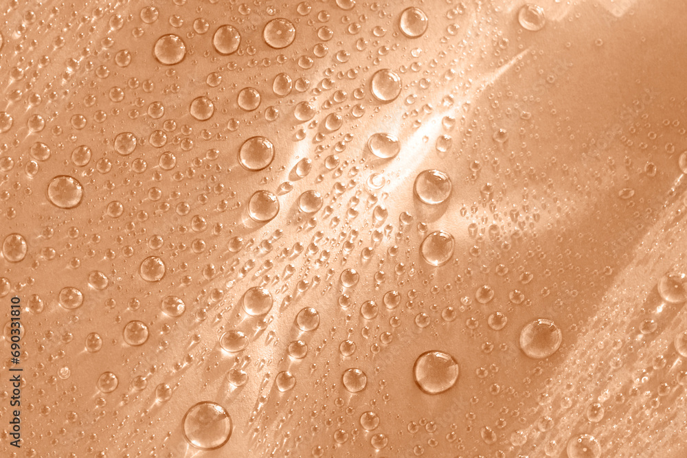 Abstract cosmetic background of a drop of moisturizing liquid on a pink background. Moisturizer tonic, lotion, serum. Beautiful trendy peach fuzz color background. Abstract cosmetic background of a drop of moisturizing liquid on a pink background. Moisturizer tonic, lotion, serum. Beautiful trendy peach fuzz color background.