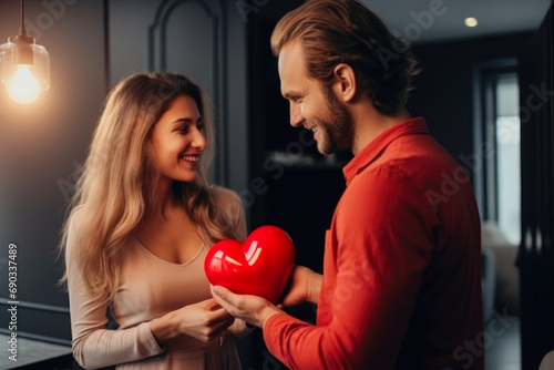 Caucasian couple on Valentine's day. Woman and man give heart to each other. Showing love and affection. Celebration love in modern hotel room.