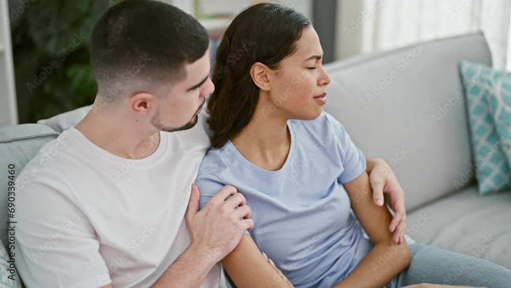 Beautiful couple hugging, supporting each other in love, sitting on home sofa sharing a tender moment Beautiful couple hugging, supporting each other in love, sitting on home sofa sharing a tender moment