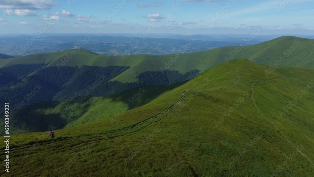 A drone view of a tourist hiking along a long mountain ridge. Beautiful shots of the green summer Carpathians. A drone view of a tourist hiking along a long mountain ridge. Beautiful shots of the green summer Carpathians.