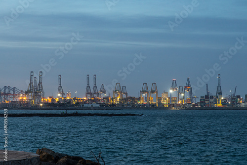 Cranes with beautiful lighting in the port on the blue sea in the evening
