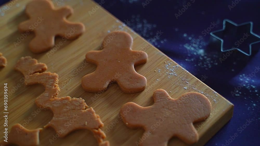 Blanks of gingerbread men made from dough lie on the table on a board, metal cookie molds lie on the table, a branch of the New Year tree Blanks of gingerbread men made from dough lie on the table on a board, metal cookie molds lie on the table, a branch of the New Year tree