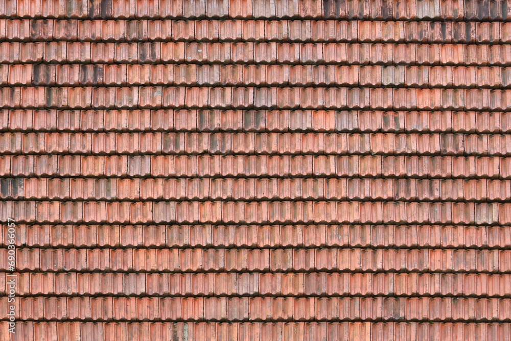 Close up of red terracotta roof shingles with some mildew. Background texture of old roofing material