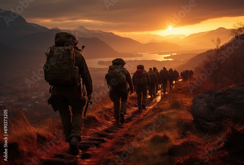 As the sun sets behind the fog-covered mountains, a group of hikers make their way along a winding path, surrounded by the vast expanse of the outdoor sky