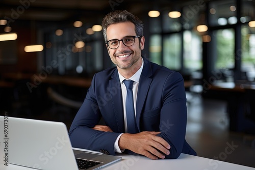 Smiling young professional business man at workplace working on laptop.